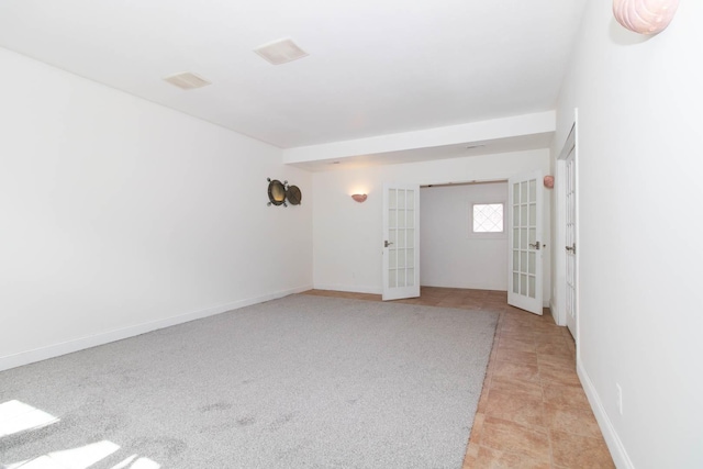 spare room featuring light colored carpet, baseboards, and french doors