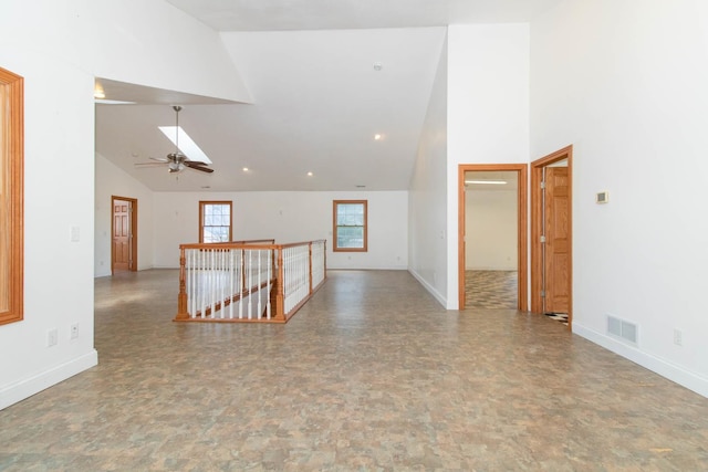 unfurnished room with baseboards, visible vents, and high vaulted ceiling