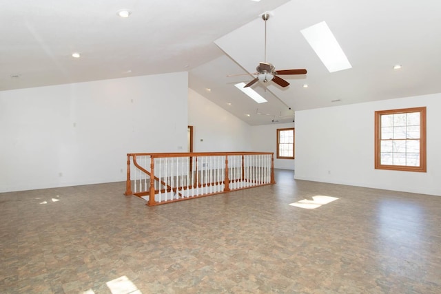 unfurnished room with high vaulted ceiling, a skylight, ceiling fan, baseboards, and recessed lighting