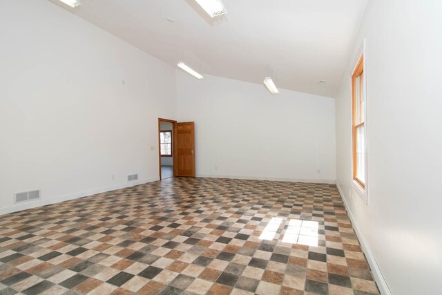 spare room with high vaulted ceiling, baseboards, and visible vents