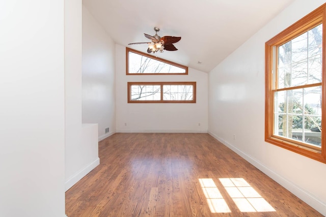 spare room featuring wood finished floors, a healthy amount of sunlight, lofted ceiling, and ceiling fan
