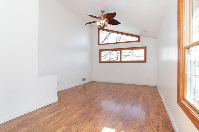 empty room featuring lofted ceiling, baseboards, wood finished floors, and ceiling fan
