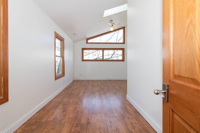 unfurnished room with baseboards, wood finished floors, and vaulted ceiling with skylight