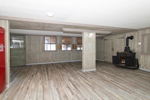 below grade area with wooden walls, wood finished floors, and a wood stove
