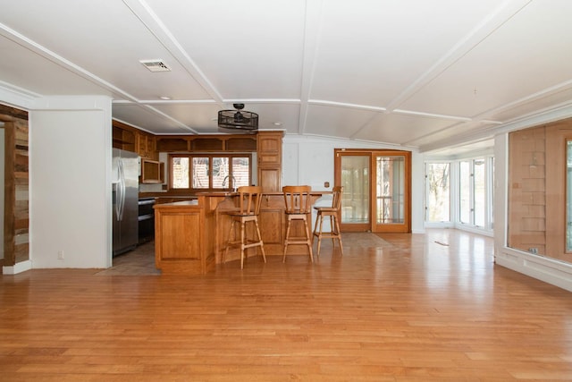 kitchen with stainless steel fridge with ice dispenser, open floor plan, visible vents, and light wood-style flooring
