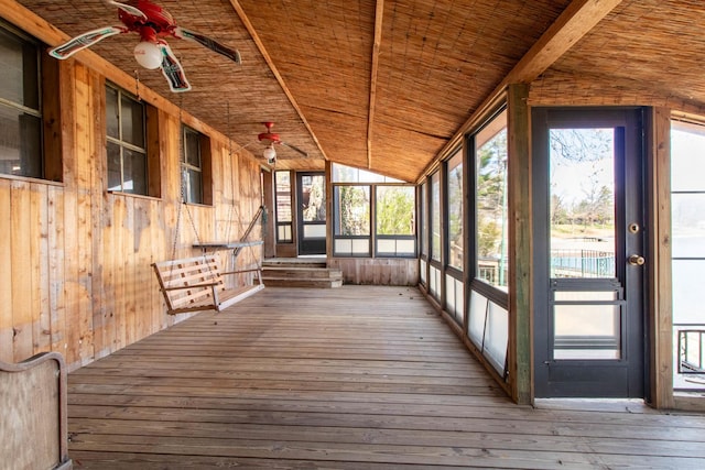unfurnished sunroom with beamed ceiling, a ceiling fan, and a healthy amount of sunlight