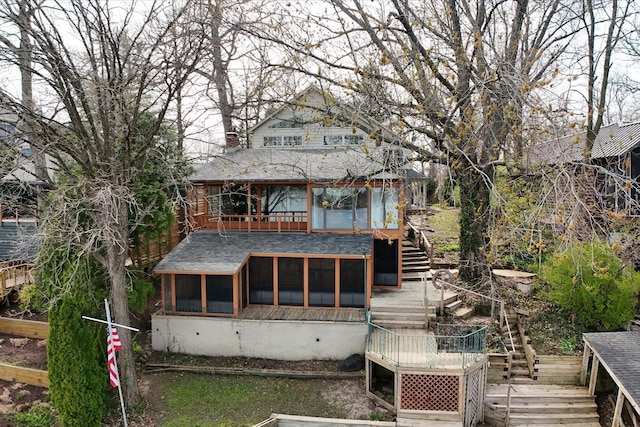 rear view of house featuring stairway, a deck, a sunroom, and a shingled roof