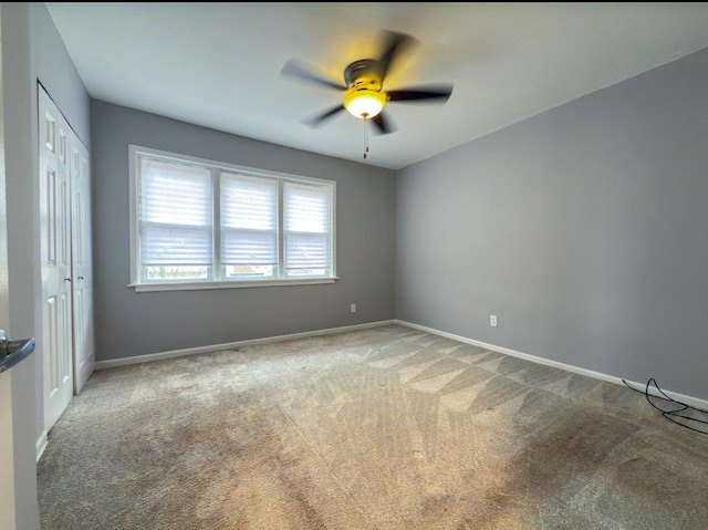 empty room with light colored carpet, baseboards, and ceiling fan
