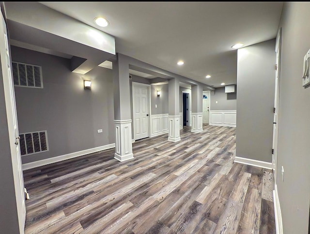 below grade area featuring dark wood-style flooring, wainscoting, visible vents, and recessed lighting