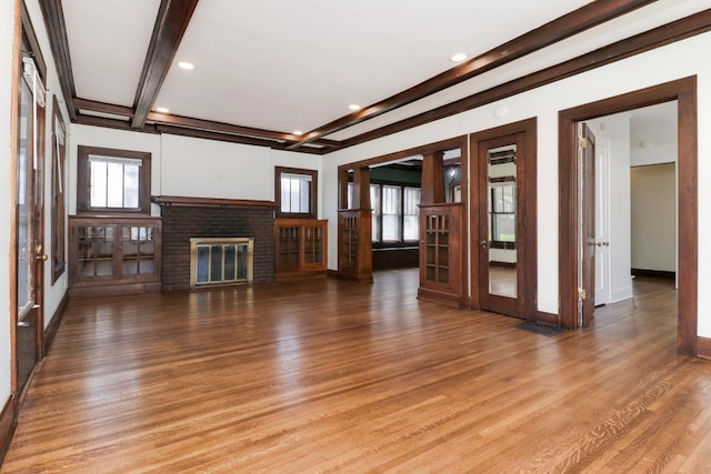 unfurnished living room featuring baseboards, recessed lighting, a fireplace, light wood-style floors, and beamed ceiling