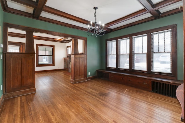 unfurnished room featuring a chandelier, coffered ceiling, and a healthy amount of sunlight