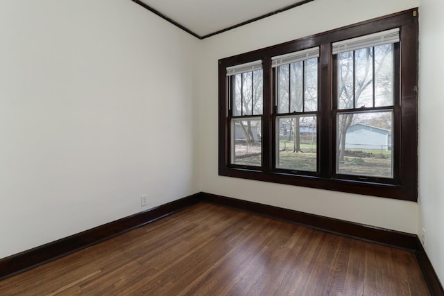 unfurnished room with dark wood-style flooring, baseboards, and ornamental molding
