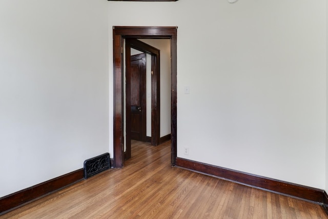 spare room featuring light wood-style floors, visible vents, and baseboards