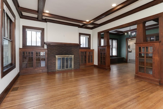 unfurnished living room with visible vents, a fireplace, beam ceiling, wood finished floors, and coffered ceiling