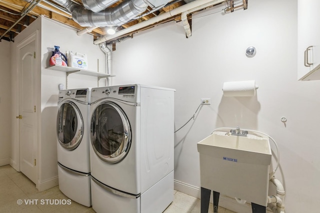 washroom with independent washer and dryer, laundry area, a sink, and baseboards