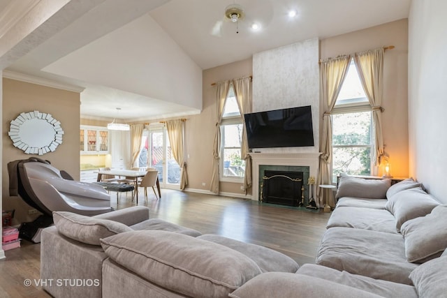 living area featuring high vaulted ceiling, plenty of natural light, a tile fireplace, and wood finished floors