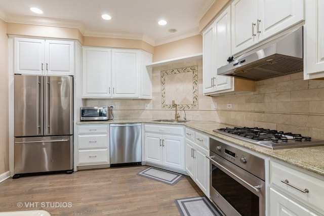 kitchen with crown molding, white cabinets, under cabinet range hood, a sink, and stainless steel appliances