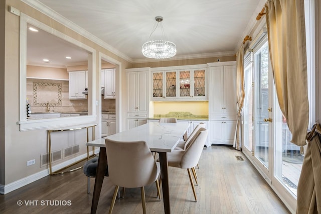 dining area with baseboards, ornamental molding, a chandelier, dark wood-type flooring, and visible vents