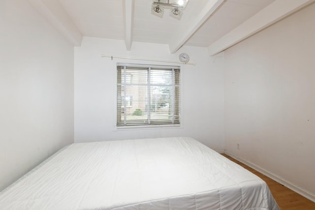 bedroom featuring beamed ceiling, baseboards, and wood finished floors