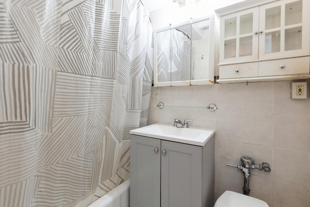 bathroom featuring a shower with curtain, tile walls, toilet, vanity, and decorative backsplash