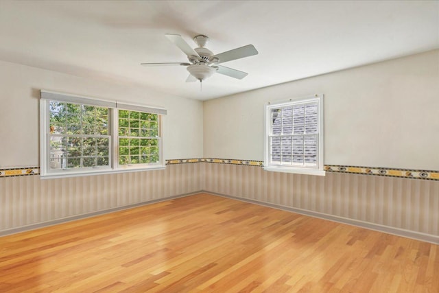 empty room featuring wood finished floors, a wainscoted wall, and ceiling fan