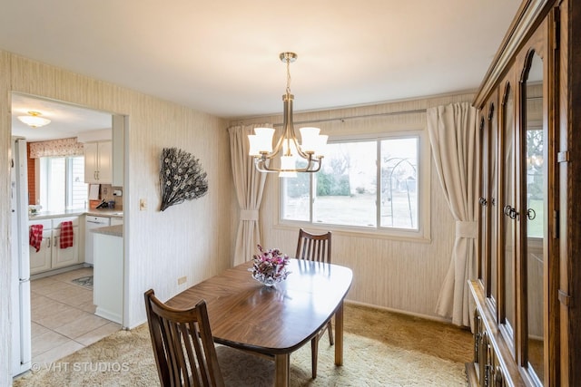 dining space with a chandelier and wallpapered walls