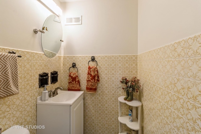 bathroom featuring tile walls, a wainscoted wall, vanity, and toilet
