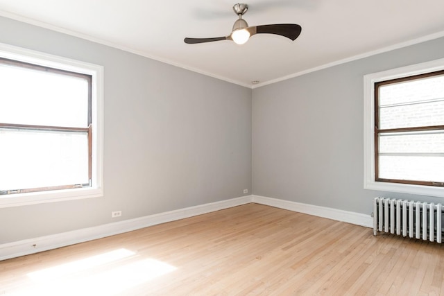 empty room with ornamental molding, light wood-style flooring, radiator, and baseboards