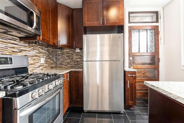 kitchen with decorative backsplash, appliances with stainless steel finishes, granite finish floor, and light stone countertops