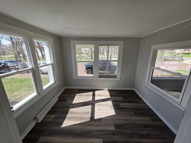 spare room with dark wood-type flooring, baseboards, and a baseboard heating unit