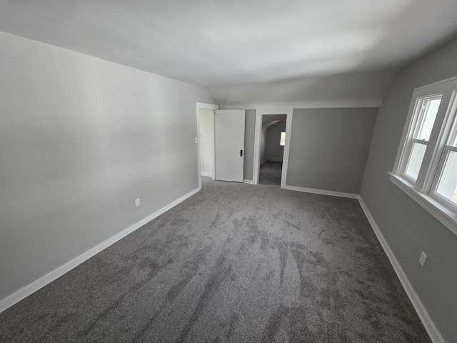 unfurnished bedroom featuring carpet flooring, baseboards, and lofted ceiling
