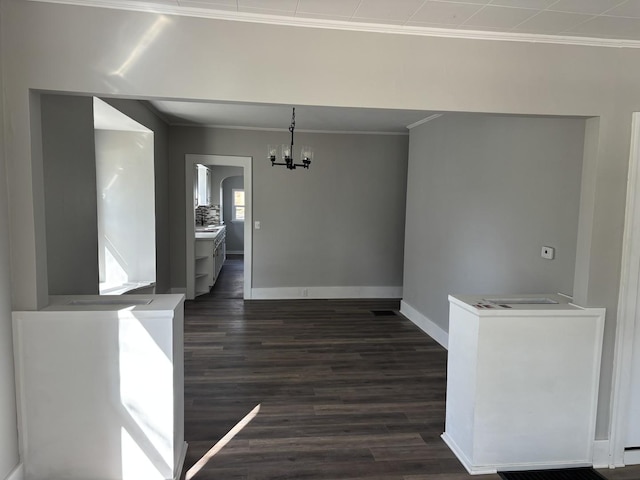 unfurnished dining area featuring baseboards, arched walkways, an inviting chandelier, ornamental molding, and dark wood finished floors