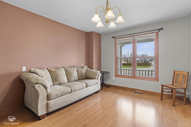 living area featuring baseboards, wood finished floors, a notable chandelier, and visible vents