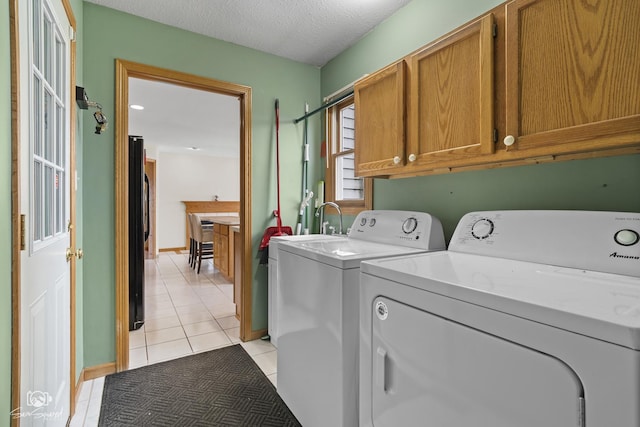 clothes washing area featuring cabinet space, light tile patterned floors, washing machine and dryer, and a textured ceiling