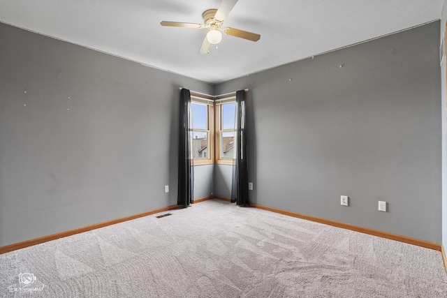 carpeted empty room with visible vents, baseboards, and a ceiling fan
