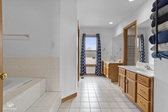bathroom with a sink, tile patterned floors, two vanities, and tiled tub