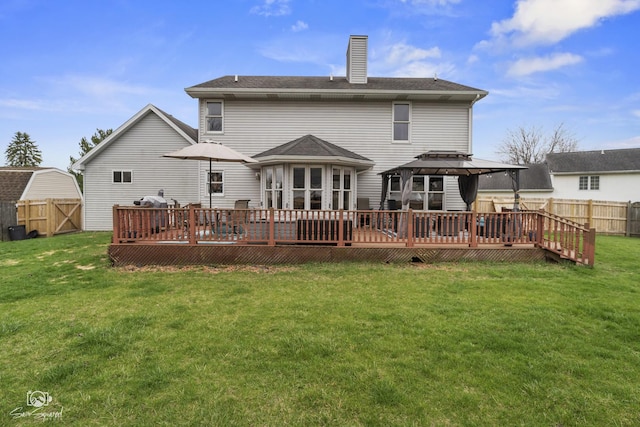 rear view of property with a fenced backyard, a deck, a lawn, and a chimney