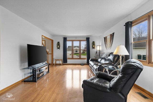 living room with visible vents, baseboards, and light wood-style floors