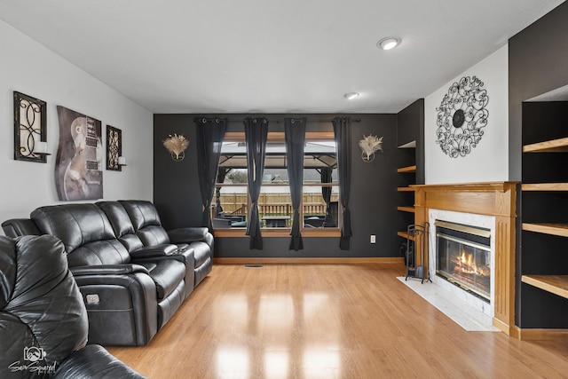 living area with a high end fireplace, baseboards, and wood finished floors