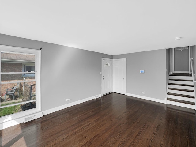 unfurnished living room with dark wood-type flooring, stairway, visible vents, and baseboards