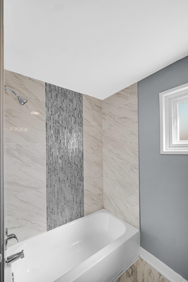 bathroom featuring marble finish floor, baseboards, and bathtub / shower combination
