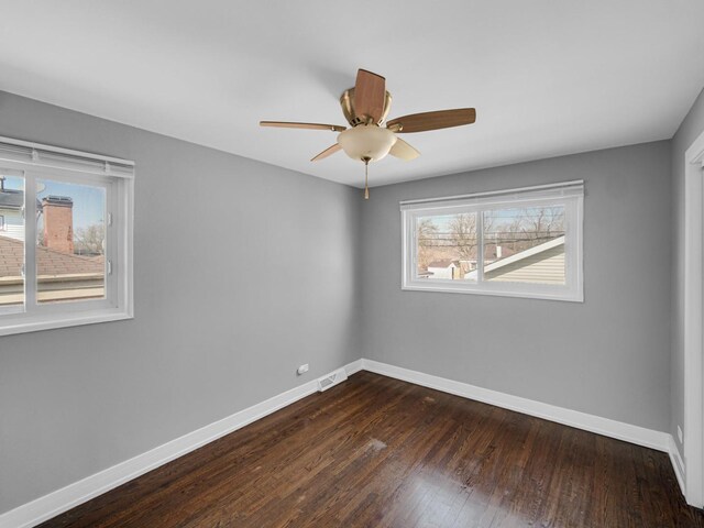 unfurnished room with ceiling fan, baseboards, visible vents, and dark wood-style floors