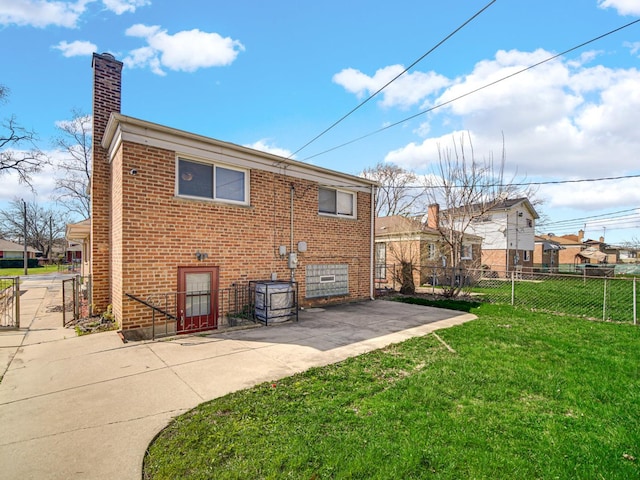rear view of house featuring brick siding, a lawn, a patio, and fence