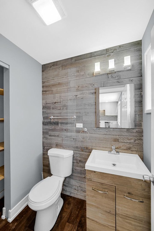 bathroom featuring toilet, tile walls, baseboards, wood finished floors, and vanity