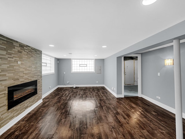 basement featuring wood finished floors, electric panel, a fireplace, baseboards, and recessed lighting