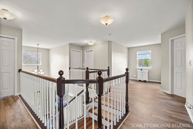 hall featuring an upstairs landing, a chandelier, baseboards, and wood finished floors