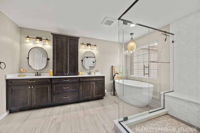 bathroom featuring a freestanding bath, double vanity, a shower stall, and baseboards