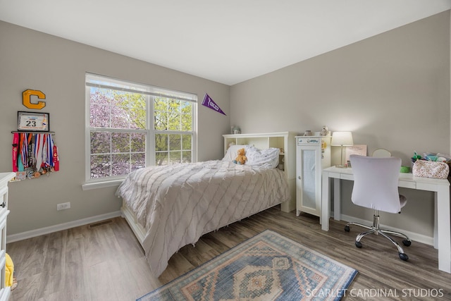 bedroom featuring wood finished floors, an office area, and baseboards