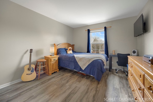 bedroom with wood finished floors, baseboards, and an office area