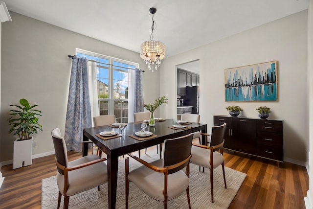 dining space featuring a chandelier, dark wood-style floors, and baseboards